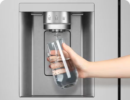 A person is getting water from the refrigerator dispenser in a cup