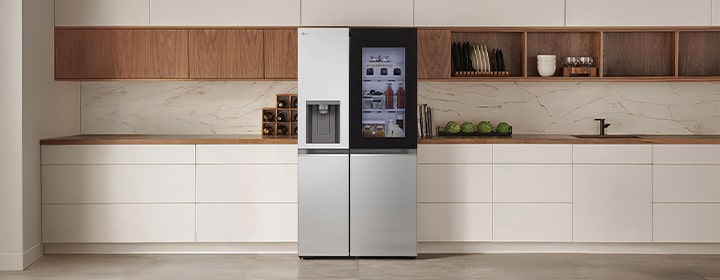 LG fridge freezer with InstaView door displayed in a modern kitchen interior with clean cabinetry and warm wood accents.