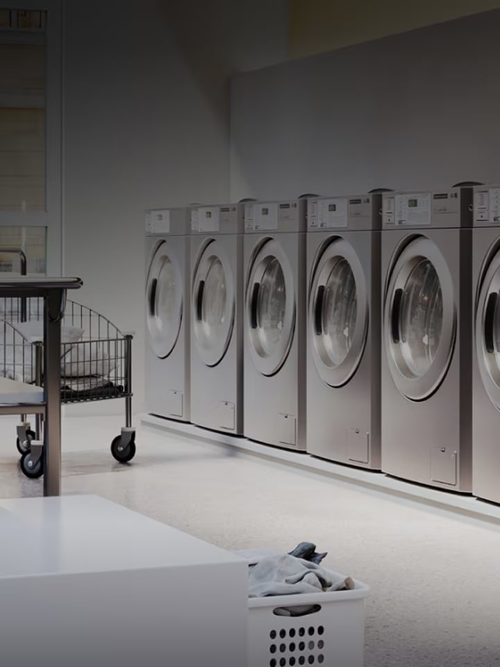 Commercial laundry room with multiple stainless steel washers lined up in a clean, modern space