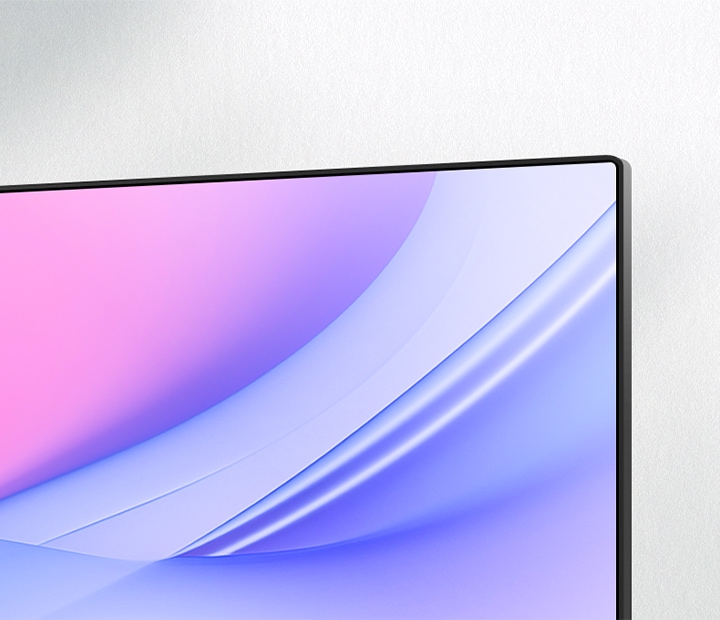 A close-up angled view of a monitor's upper-right corner, showcasing its ultra-slim bezel and seamless screen design. The display features a smooth pink-to-blue gradient, emphasising a clean and modern aesthetic ideal for minimalistic setups.