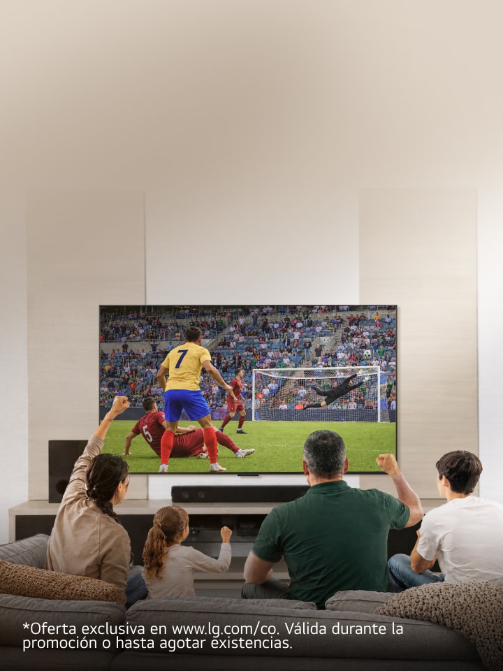 Una familia sentada en el sofá de la sala disfruta y celebra un partido de fútbol en una pantalla grande.