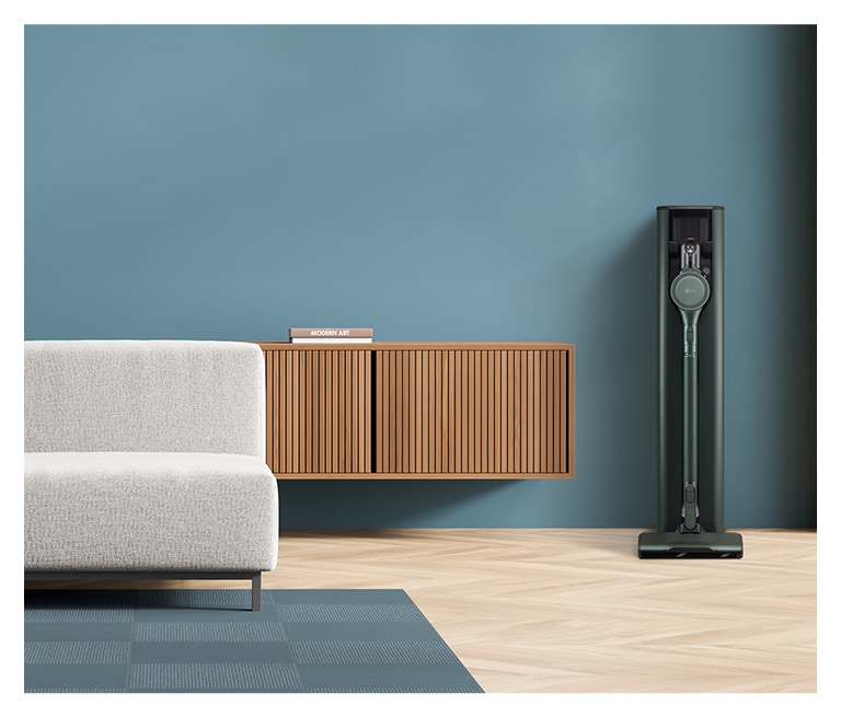 畫面顯示置於藍色現代客廳的蒼林綠的 LG Objet Collection A9TS 蒸氣無線吸塵機。
