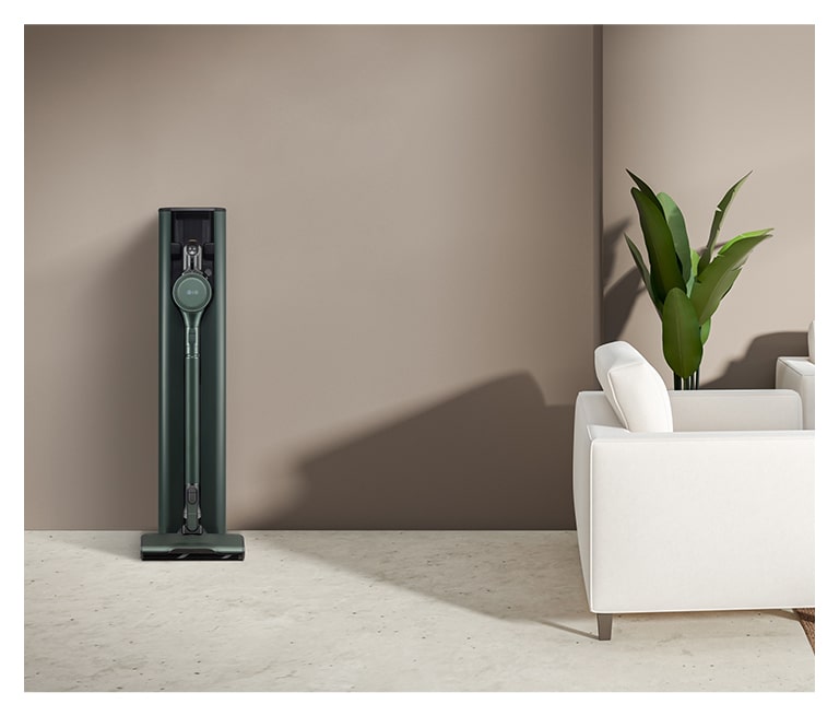 畫面顯示置於啡色現代客廳的蒼林綠的 LG Objet Collection A9TS 蒸氣無線吸塵機。