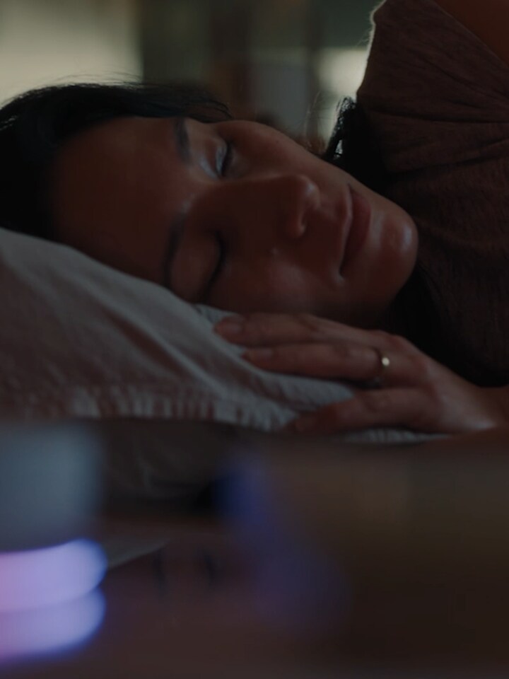 A man and a woman lie intertwined on the living room sofa while the LG TV plays a cooking channel. After the woman falls asleep, the man calls out, "Hi LG," asking to play the soccer match, and the channel switches to the game.