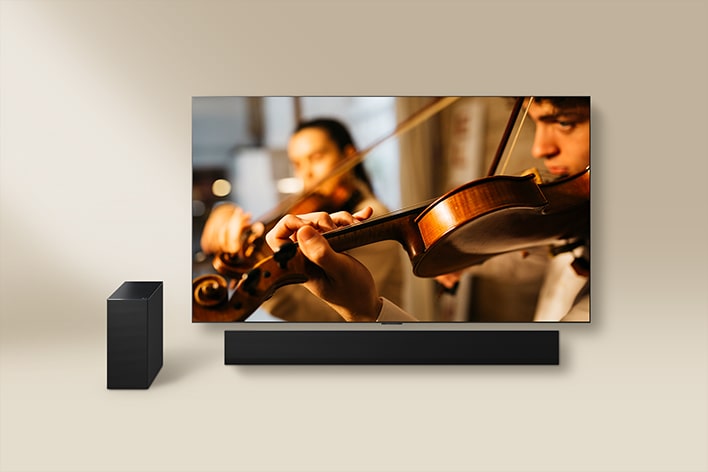 Telewizor LG widziany razem z soundbarem LG i głośnikiem zewnętrznym. Na ekranie pojawia się skrzypek.