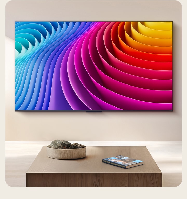 LG QNED TV zamontowany na ścianie w eleganckim, luksusowym salonie. Na ekranie widoczny jest abstrakcyjny obraz z gradientem odcieni, pokazujący, jak Dynamic QNED Color Pro odwzorowuje szeroką gamę kolorów.