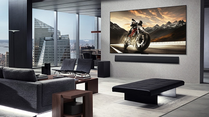 Zawieszony na ścianie telewizor LG OLED M5 TV i LG Soundbar w eleganckim apartamencie. Zero Connect Box schowany pod stolikiem.