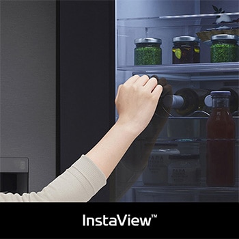 Lodówka LG GSXV90MCDE z **InstaView** Door-in-Door: dłoń sięga po butelkę przez półotwarte wewnętrzne drzwi, przy widocznej podświetlonej komorze.