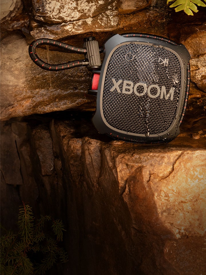 Uma imagem do XG2T em pé sobre uma rocha com uma cascata ao fundo.