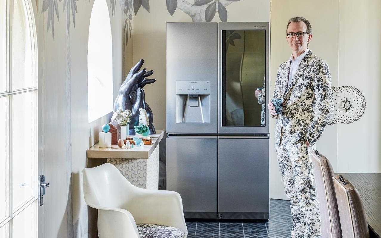 Ashley Hicks standing in his dining room with the LG SIGNATURE instaview door-in-door refrigerator in the kitchen