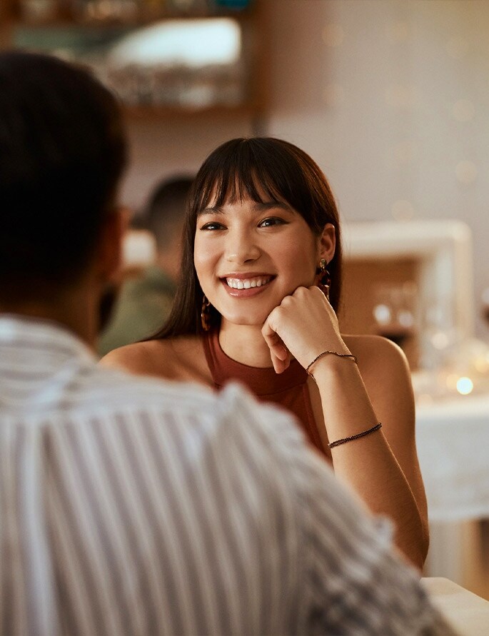 An over the shoulder image of woman looking and smiling at her date.