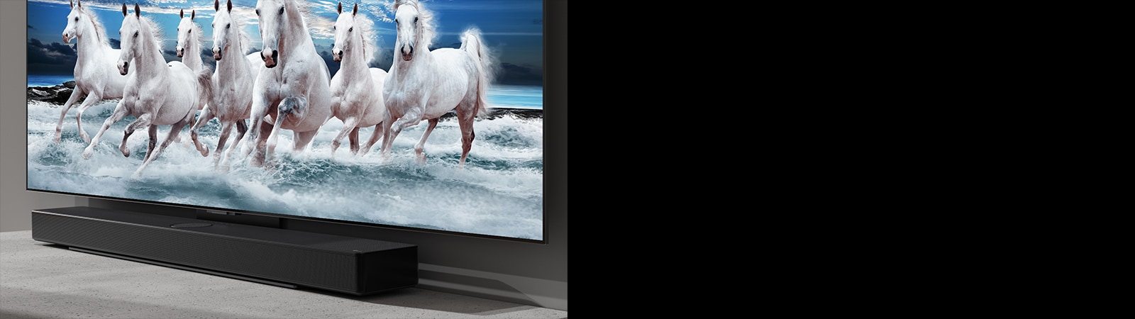 На белом столе расположены саундбар и телевизор, а на экране телевизора показано 7 белых лошадей.