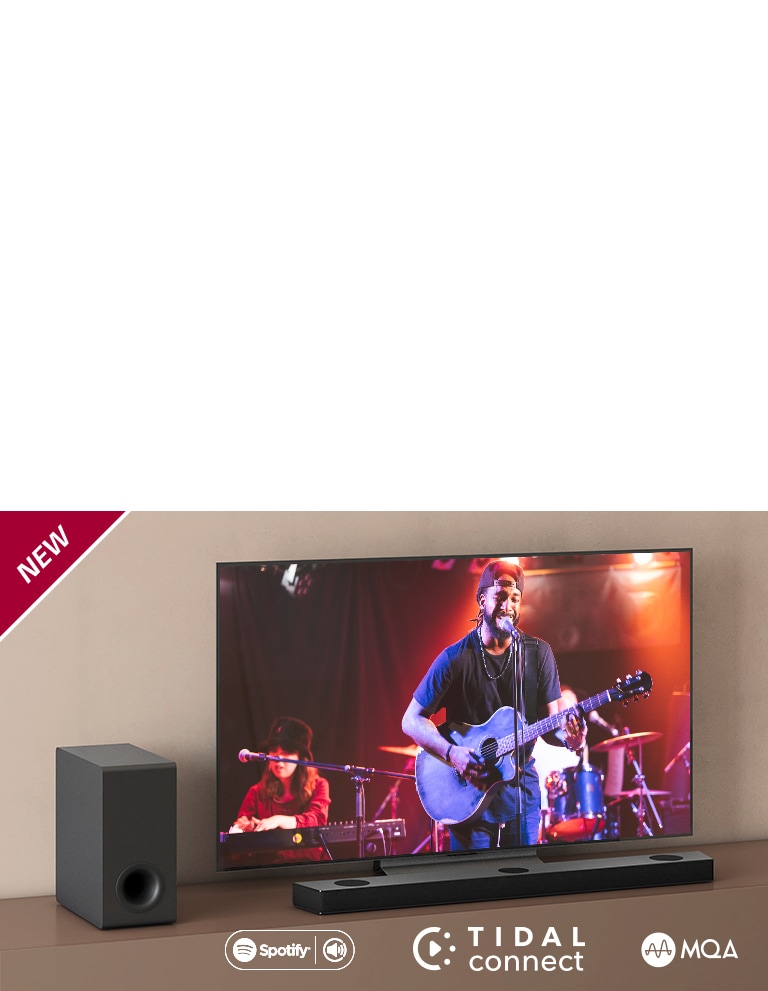 Телевизор LG стоит на серой полке, перед телевизором стоит саундбар LG S90QY. Слева от телевизора стоит сабвуфер. На телевизоре демонстрируется сцена концерта. НОВАЯ маркировка показана в верхнем левом углу.