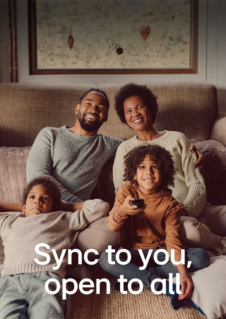 En bild av en familj med fyra personer som sitter på golvet framför den mysiga bruna soffan och tittar rakt fram och skrattar medan de tittar på TV. Orden "Synkas med dig, öppen för alla" visas över bilden i ett vitt teckensnitt. 