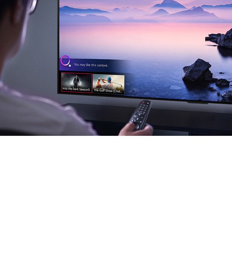 Closeup of a man choosing what to watch on TV with a remote control, with TV showing landscape