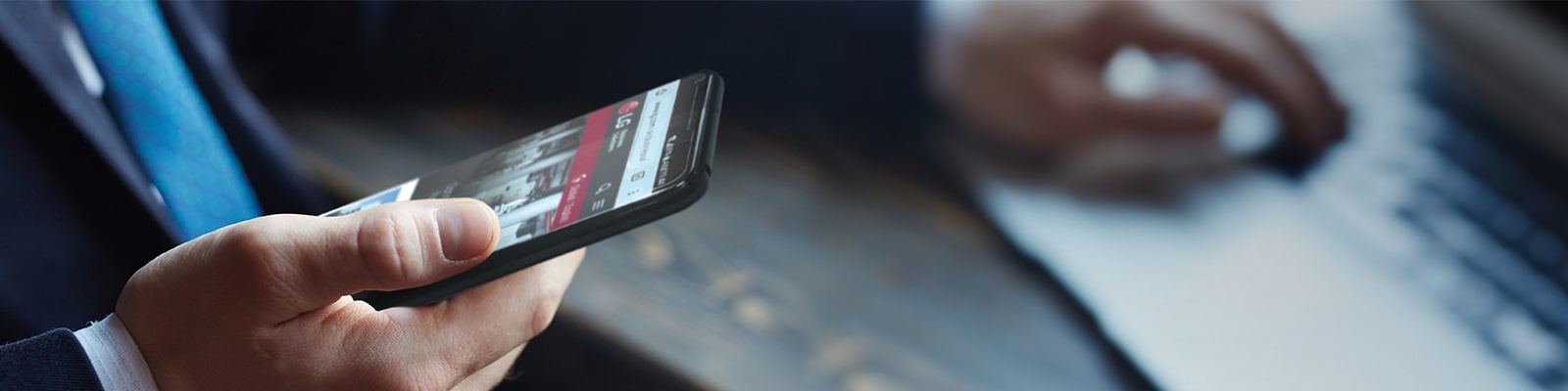 A man in a suit holds a smartphone in his right hand, displaying the LG website.