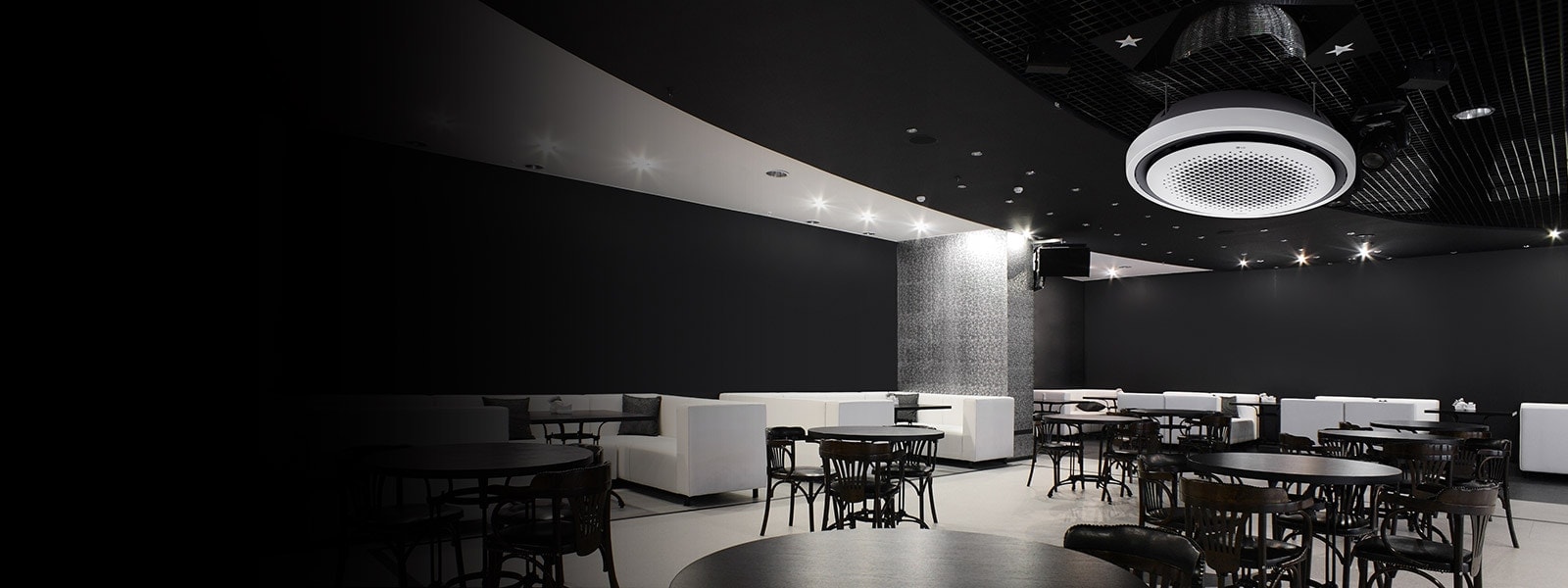 Black and white tone dining area with tables, chairs, and a sofa displayed. LG Round Cassette air conditioner(ac) mounted on the ceiling. 