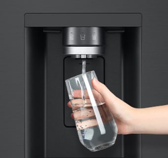 A person is getting water from the refrigerator dispenser in a cup