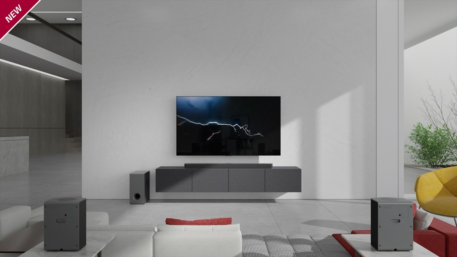 The sound bar is placed on gray cabinet with a TV hung on the wall in the living room. A wireless subwoofer is placed on the floor on the left side and the sunlight comes in from the right side of the picture. A white and red colored long sofa is placed facing the TV and sound bar. NEW mark is shown in the top left corner.