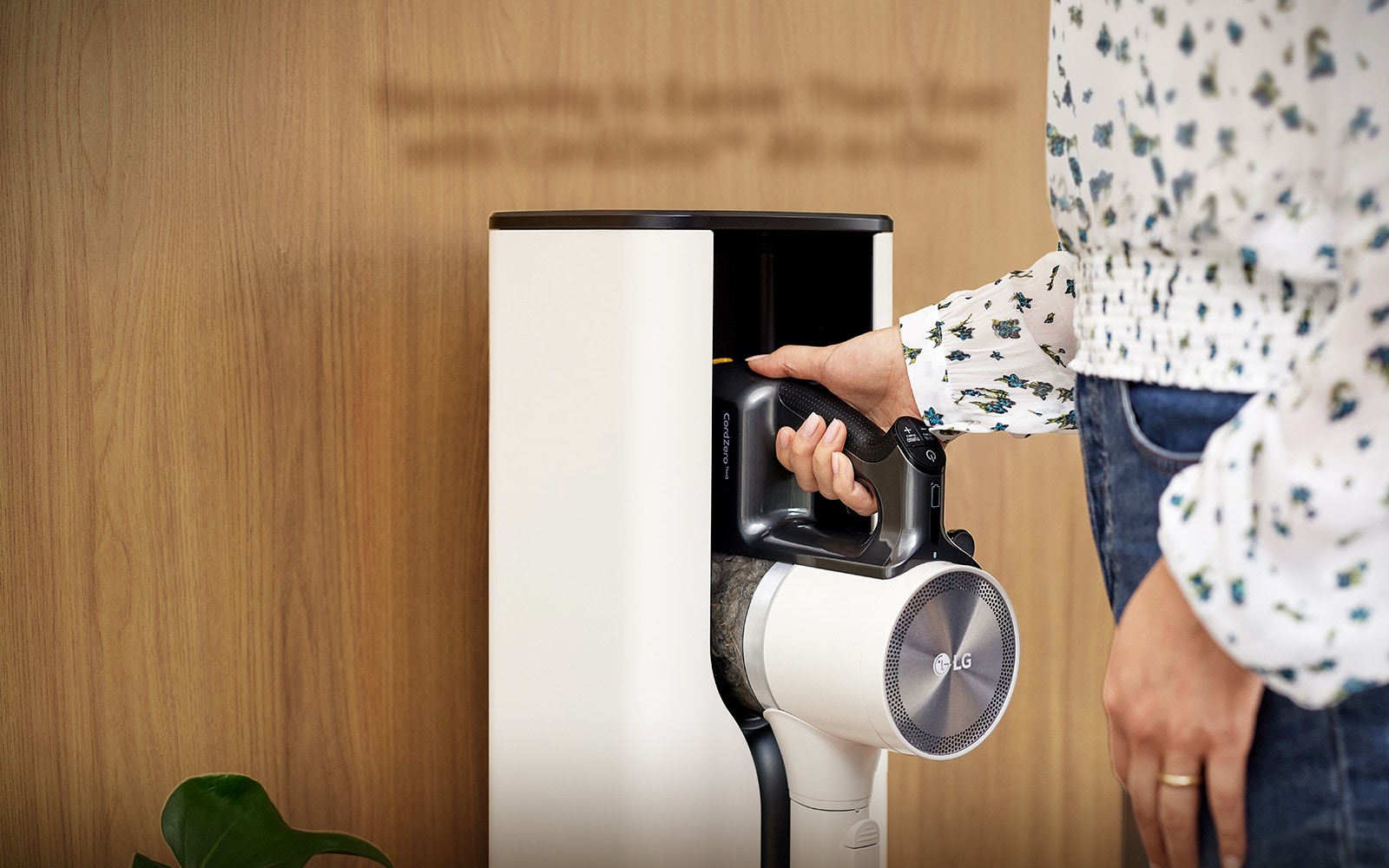 A woman is putting in a Cordzero™ Vacuum cleaner in a docking station.