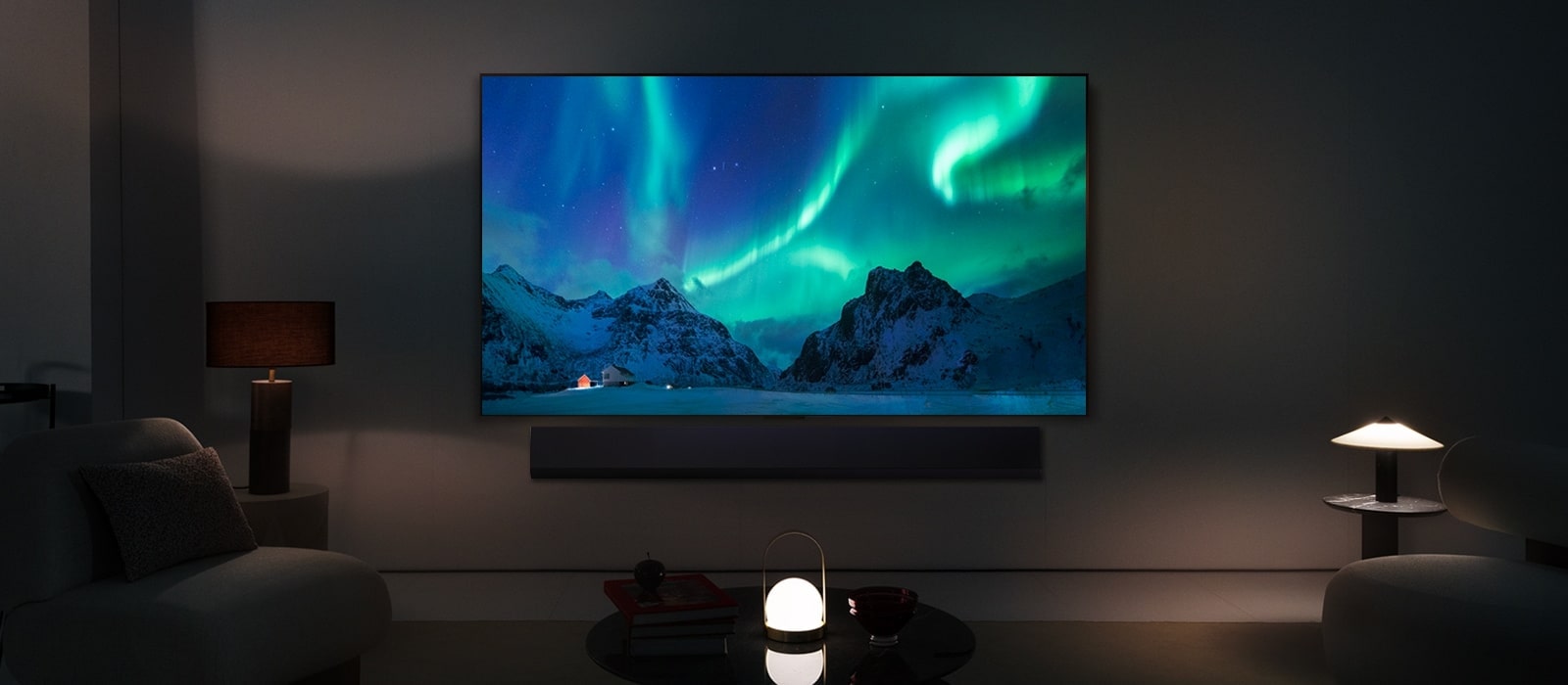 LG OLED TV والسماعات المنفصلة LG Soundbar في غرفة معيشة عصرية خلال الليل. صورة الشفق القطبي تظهر على الشاشة بمستويات السطوع المثالية.