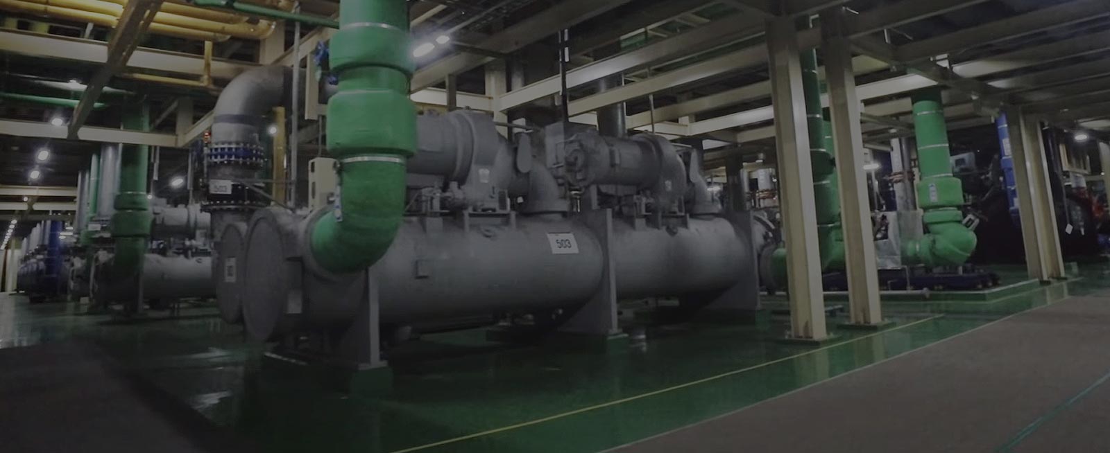 A substantial gray-toned LG Chiller unit commands attention in a machine-filled room, its presence accentuated by green/blue pipes.