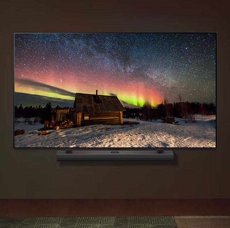 LG TV and LG Soundbar in a modern living space in nighttime. The screen image of the aurora borealis is displayed with the ideal brightness levels.