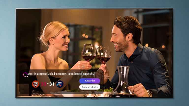 A man and a woman toast on a TV screen as a sports alert appears