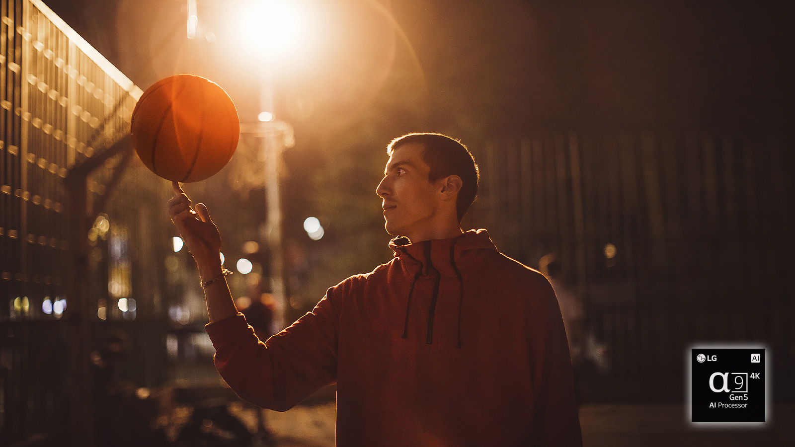 Un homme sur un terrain de basketball la nuit fait tourner un ballon de basketball sur son doigt