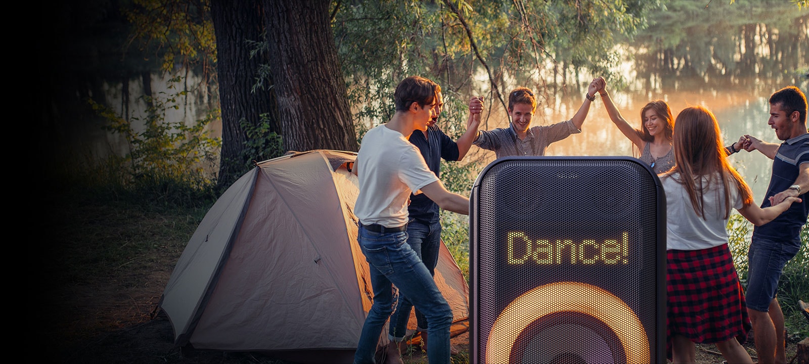 Gros plan de l’éclairage dynamique à pixels Il affiche le texte Dance! En dessous, l’éclairage circulaire multicolore orange est allumé. Derrière le haut-parleur, des personnes dansent sur la plage.