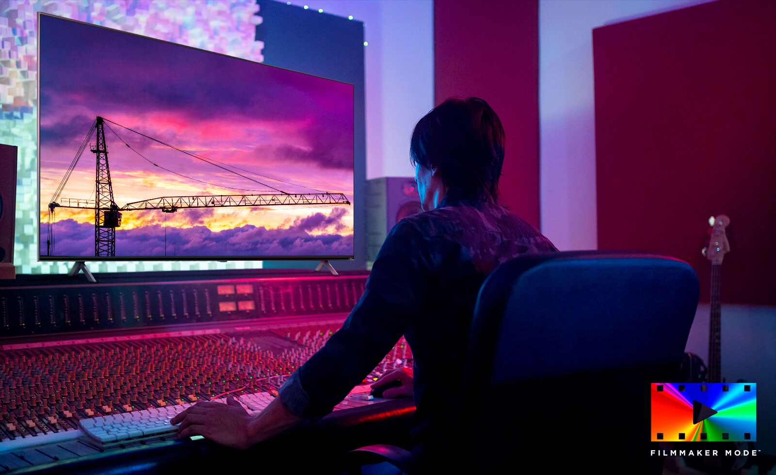 Un director de cine está mirando un gran monitor de televisión, editando algo. La pantalla de televisión muestra una grúa torre en un cielo violeta. El logotipo del modo FILMAKER se encuentra en la esquina inferior derecha.