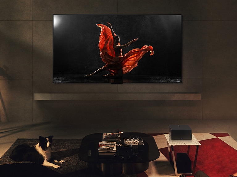 LG SIGNATURE OLED M4 und LG Soundbar in einem modernen Wohnraum bei Nacht. Es wird das Bild eines Tänzers auf einer dunklen Bühne mit der idealen Helligkeitsstufe angezeigt.