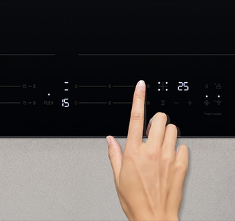 Touching the control panel of the induction cooktop.