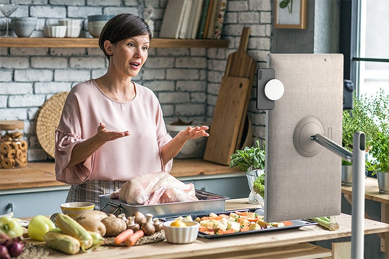 A woman is looking at StanbyME and talking. The standbyME is equipped with a mobile phone.