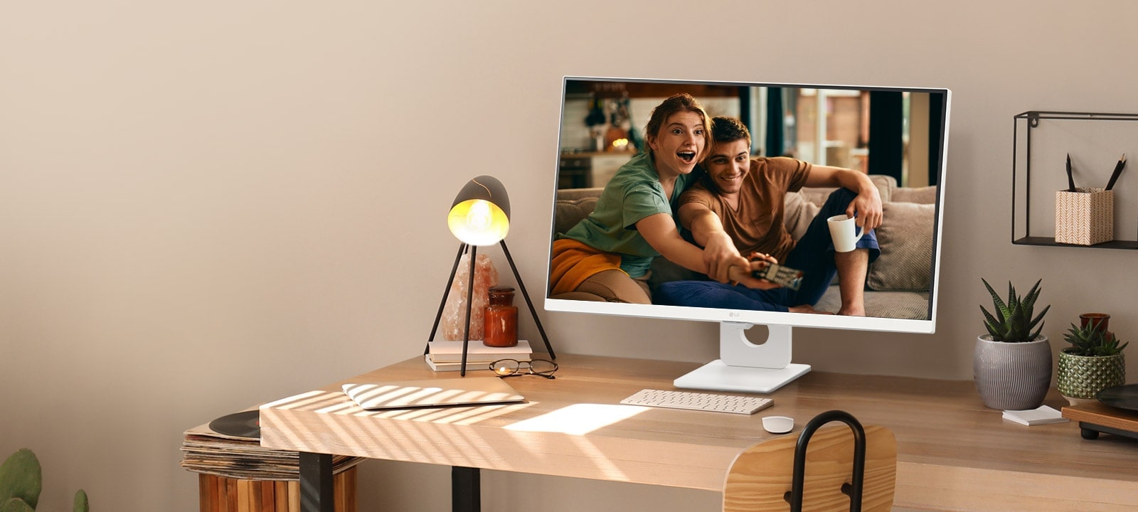 Sur un bureau à côté d’une fenêtre ensoleillée, un moniteur intelligent affiche un film sur son écran. À côté du moniteur se trouvent une lampe et une plante en pot. Sur le bureau se trouvent un clavier et une souris.