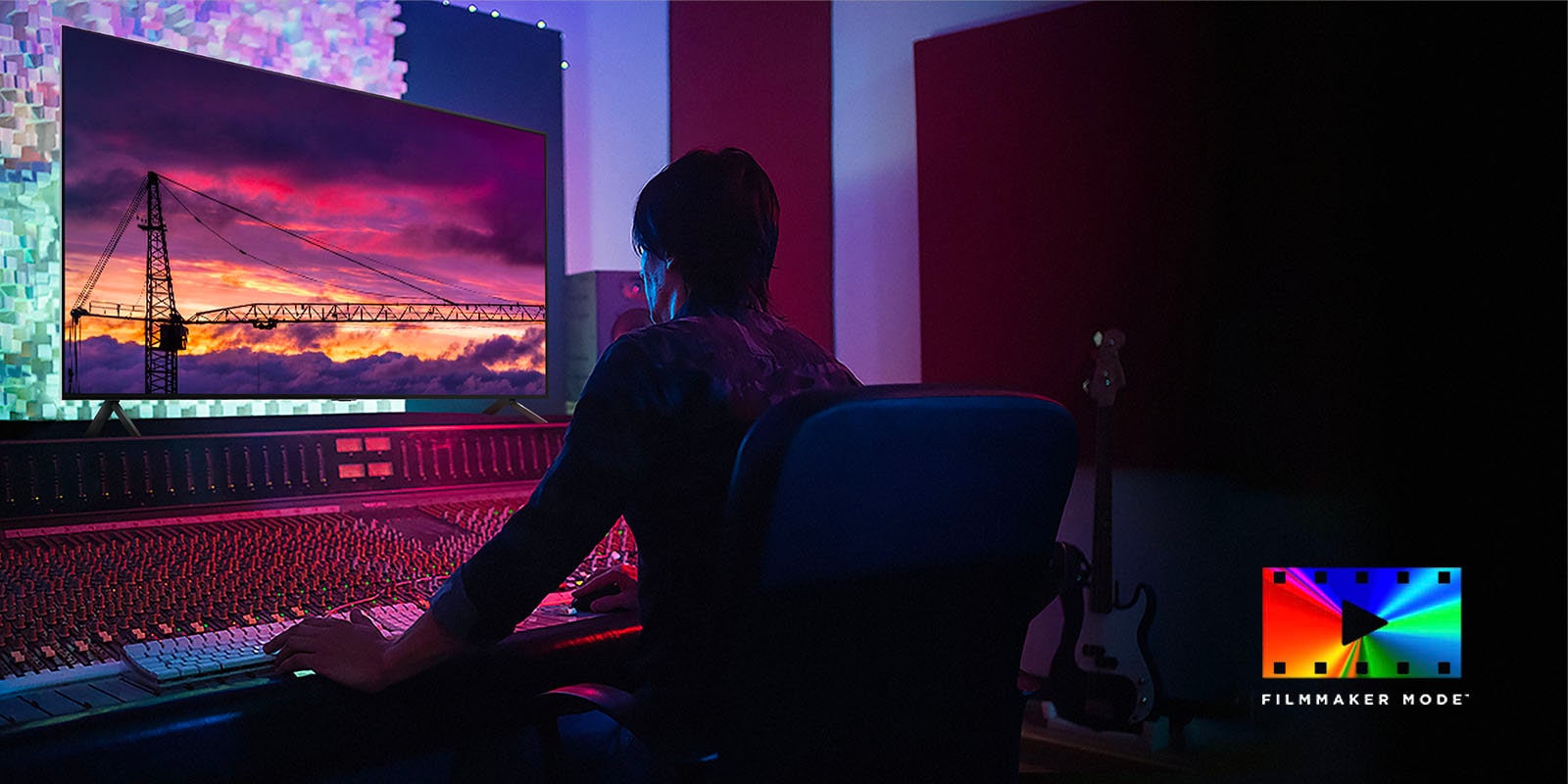 Un homme dans un studio de montage sombre regardant un LG TV affichant le coucher du soleil. En bas à droite de l’image se trouve le logo du FILMMAKER Mode.