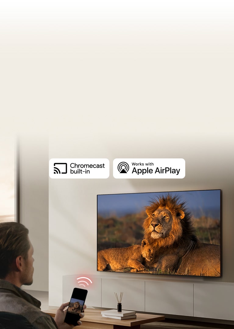 LG телевизор монтиран на стена във всекидневна, показващ лъв и лъвче. Мъж седи на преден план със смартфон в ръка, показващ същото изображение на лъвове. Точно над смартфона, насочен към телевизора се показва графика от три неонови червени извити ленти.