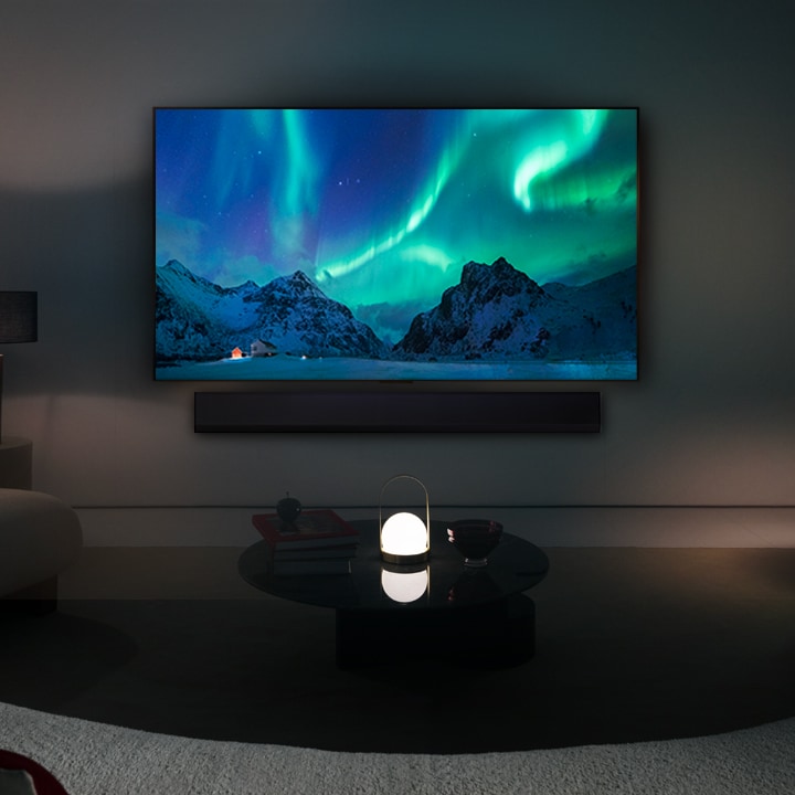 LG OLED y una barra de sonido LG en un espacio moderno durante la noche. La imagen de la pantalla de aurora boreal se muestra con los niveles de brillo ideales.