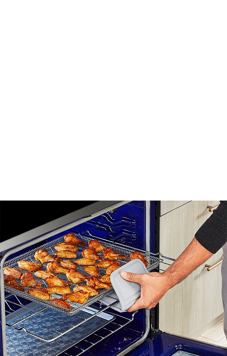 La imágen de abrir el horno y sacar una ala de pollo bien cocido.