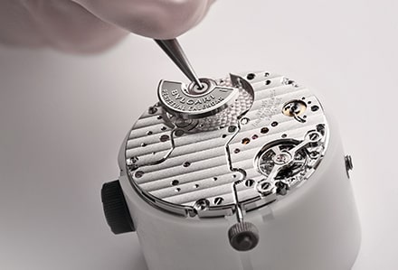 Eine Nahaufnahme zeigt einen Uhrmacher, der an einer Uhrenkomponente arbeitet.