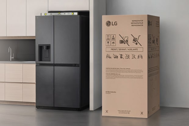 Refrigerador LG negro ubicado a la izquierda, con una caja de instalación colocada a la derecha, junto a la pared.