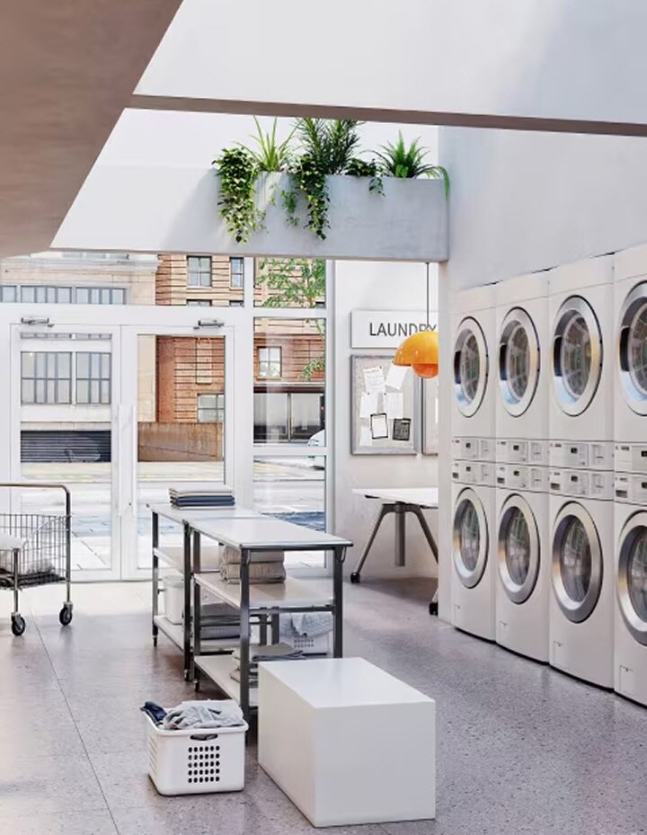 Open laundromat interior with natural light, folding tables, and multiple front-load machines