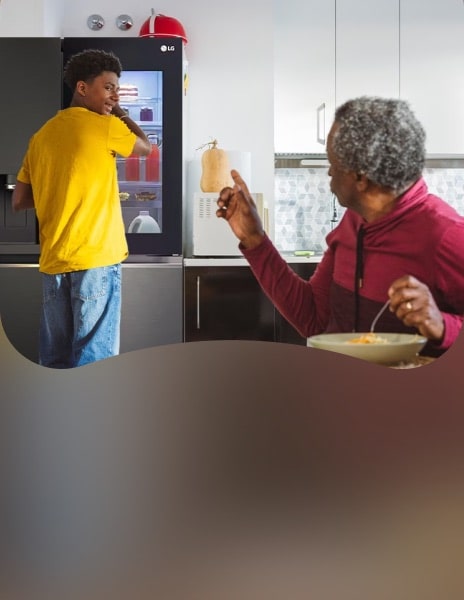 Family in modern kitchen using LG InstaView fridge freezer, father eating and son reaching into fridge, highlighting easy access and smart food organisation.
