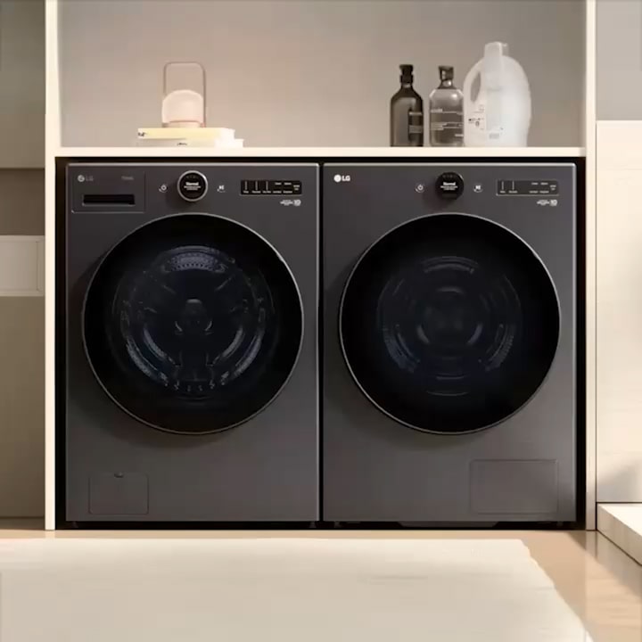 LG black Washer Dryer installed inside a cabinet, with towels placed on the right and shampoo bottles with a sink visible on the left.