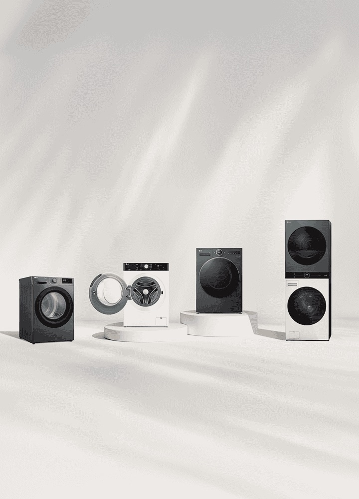 LG washer and dryer lineup in front of a beige wall. Includes a tumble dryer, front load washer with open door, washer dryer combo, and WashTower. A forest view is visible on the right.