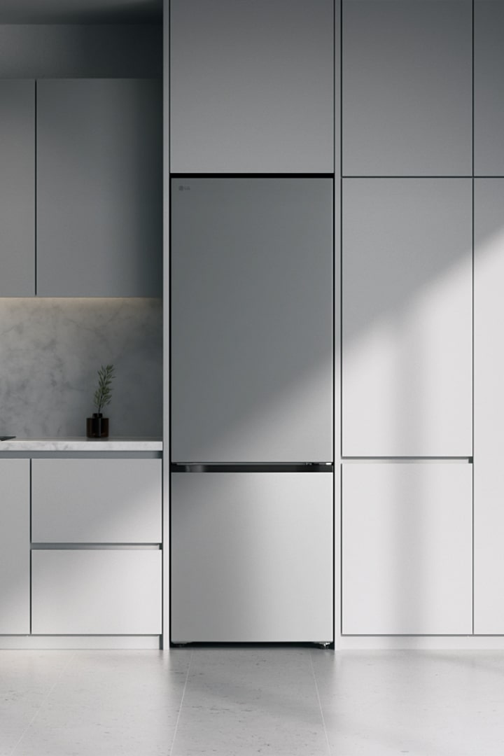 LG silver fridge freezer sliding into modern minimalist kitchen cabinetry in a modern gray kitchen with a stone backsplash.