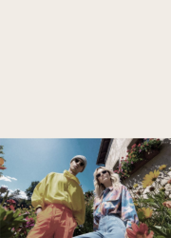 LG QNED evo AI QNED85 Mini LED with AI Picture Pro shows a low-angle outdoor lifestyle scene with two people among vivid flowers, as AI recognises and upscales each frame to 4K for clearer texture and detail.