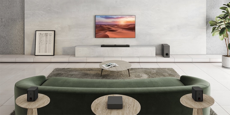 Zu sehen ist ein Fernseher, der ein Naturbild zeigt. Eine Soundbar, ein Subwoofer und 2 hintere Lautsprecher befinden sich in einem weiträumigen Wohnzimmer. Von der Soundbar geht eine Welle mit Gittermuster aus, die bildlich darstellt, wie das gesamte Wohnzimmer vermessen wird.