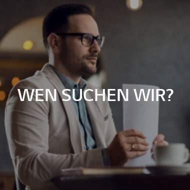 Ein Mann sitzt an einem Schreibtisch und hält einen Papierstapel