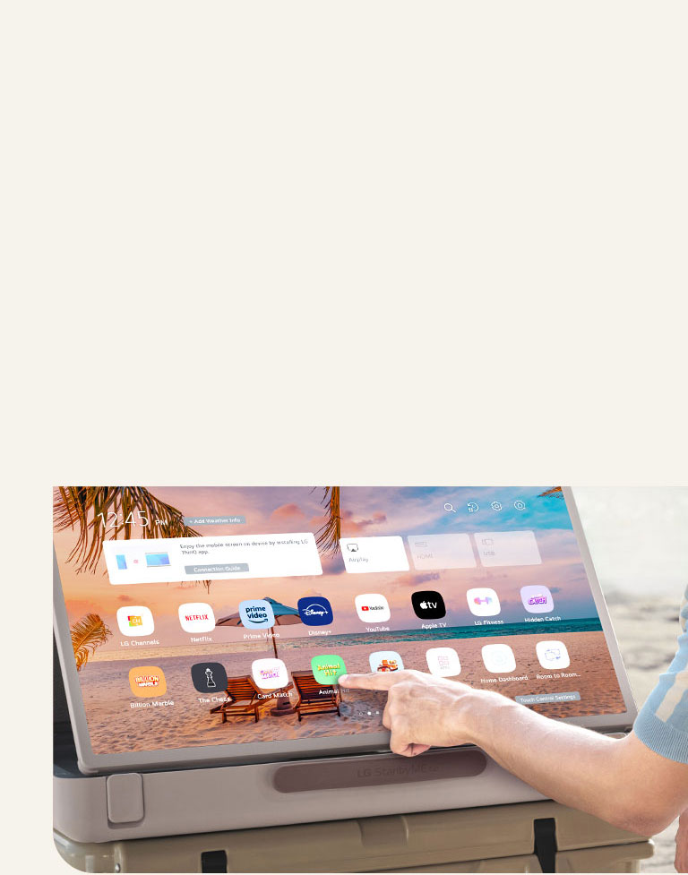 Close-up of LG StanbyME Go. The product is placed on a table, and the screen rotated horizontally. A hand is touching an icon.